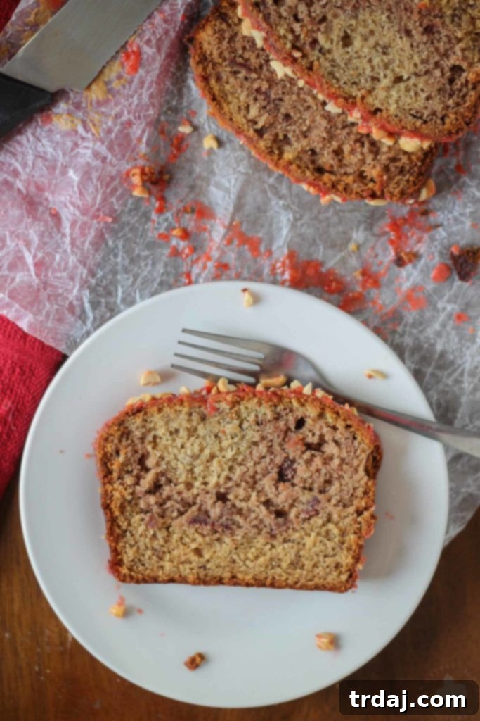 Close-up of a delicious slice of Peanut Butter and Jelly Banana Bread, ready to be enjoyed, showcasing its soft texture and flavorful swirl.