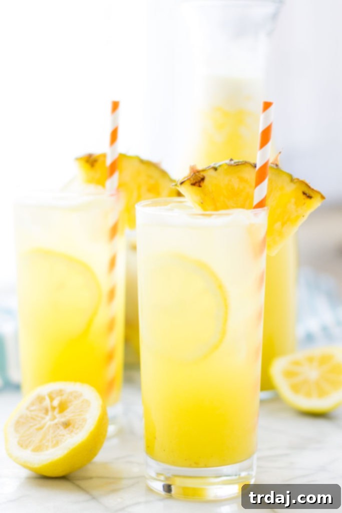 Zesty Pineapple Kick 2 Close-up of Pineapple Ginger Lemonade garnished with fresh pineapple and lemon slices, served in a tall glass with ice.