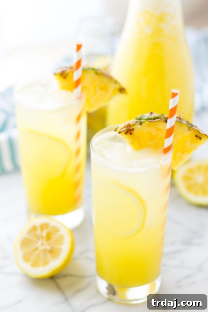Zesty Pineapple Kick 3 Refreshing Pineapple Ginger Lemonade in a glass pitcher, ready to be served over ice with pineapple and lemon slices.