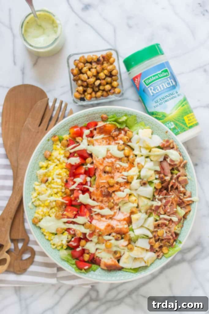 A visually stunning close-up of the BBQ Salmon Cobb Salad, arranged in classic rows to showcase each ingredient before mixing.