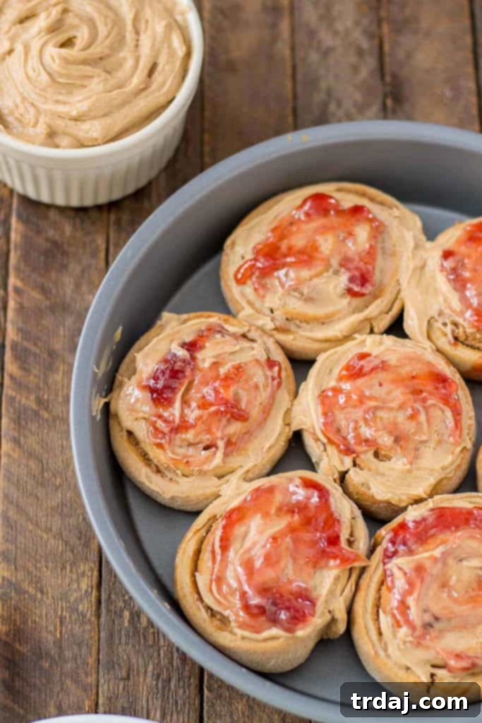 Close-up of golden brown Peanut Butter and Jelly Breakfast rolls baking in a pan, filling the kitchen with a sweet aroma. | Strawberry Blondie Kitchen