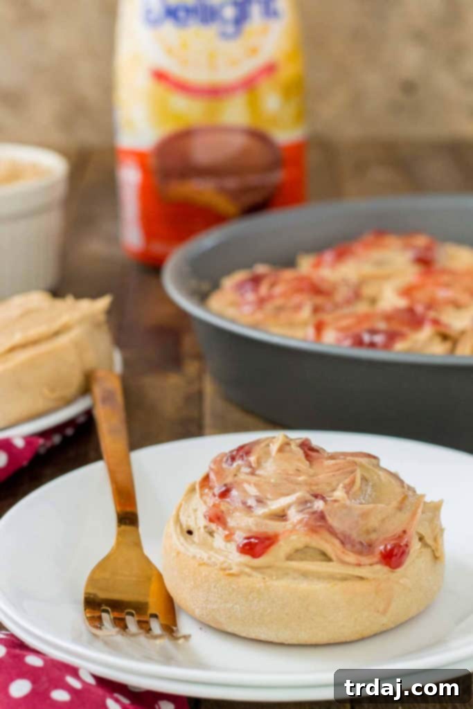 A close-up of a single Peanut Butter and Jelly Breakfast roll, showing the fluffy texture and layers of peanut butter and jelly swirl. | Strawberry Blondie Kitchen