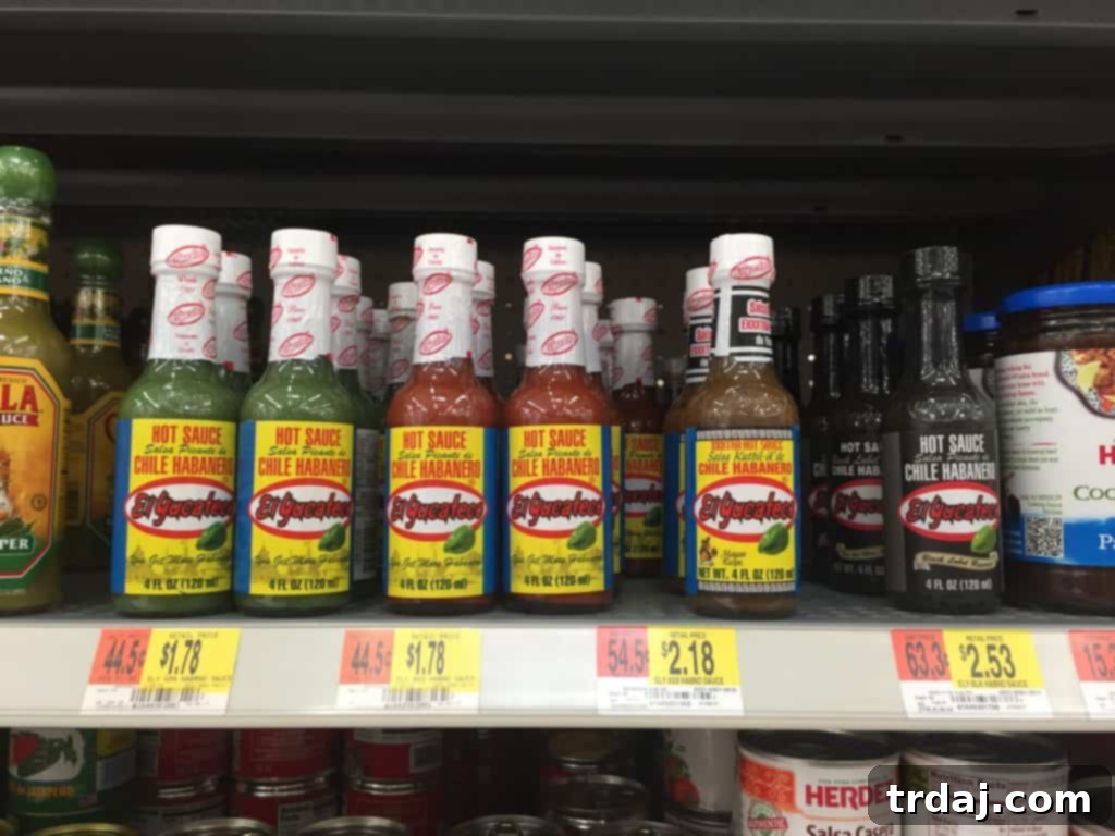 Bottles of various El Yucateco hot sauces displayed alongside a bowl of Chorizo Queso Fundido, highlighting the perfect flavor pairing.