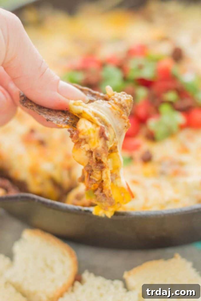 A serving of Chorizo Queso Fundido, rich with cheese and spices, next to El Yucateco hot sauce, ready for game day indulgence.