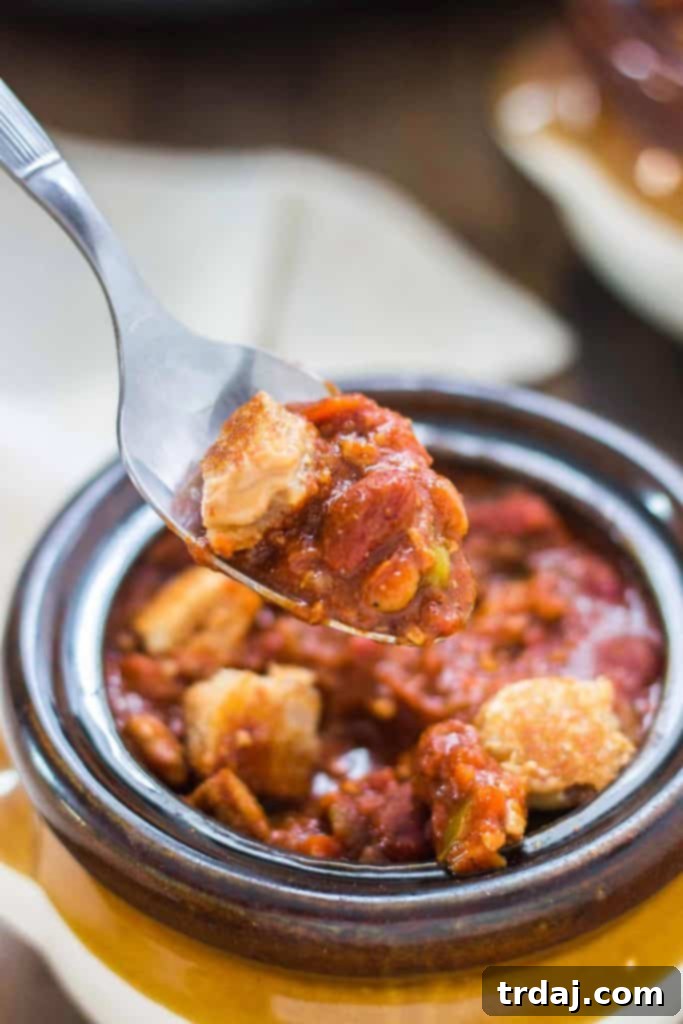 Overhead view of a comforting bowl of Crockpot Chili generously topped with crunchy peanut butter sandwich croutons and fresh cilantro