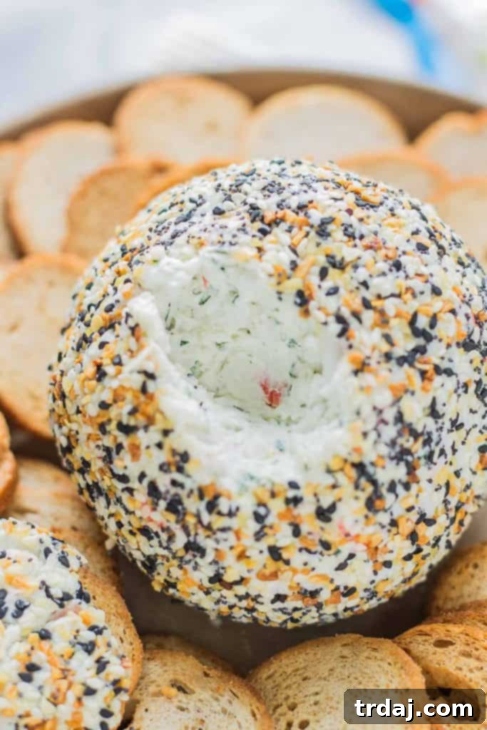 Close-up shot of the Crab and Everything Bagel Cheese Ball, showcasing its rich texture and topping, with a variety of crackers on the side.
