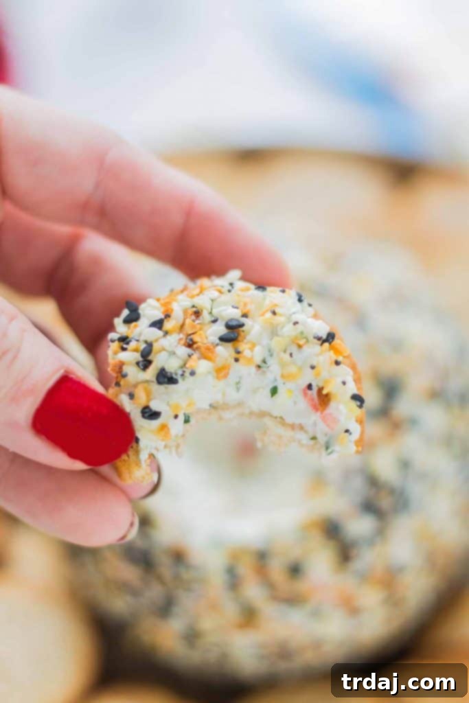 A slice of the Crab and Everything Bagel Cheese Ball showing the creamy crab and herb filling, perfectly scooped onto a cracker and ready to eat.