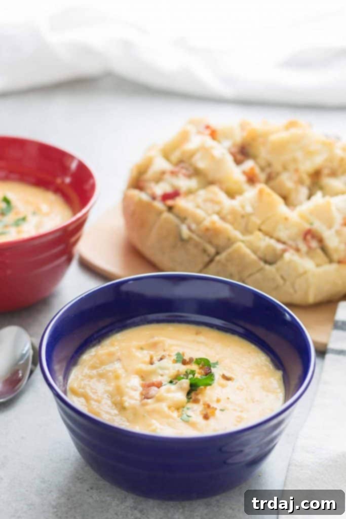 A large serving of Cheddar Bacon Ranch Pull Apart Bread, golden brown and cheesy, displayed prominently with a bowl of Idahoan soup in the background.