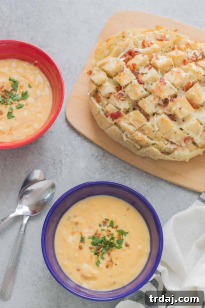 A perfectly baked Cheddar Bacon Ranch Pull Apart Bread on a cutting board with a warm, comforting bowl of Idahoan Steakhouse Soup, creating a delightful winter meal scene.