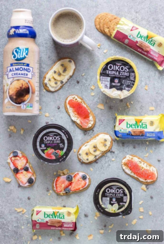 Close-up of a hand holding a Mini Breakfast Biscuit Pizza, showing a belVita biscuit base with yogurt and fresh fruit.