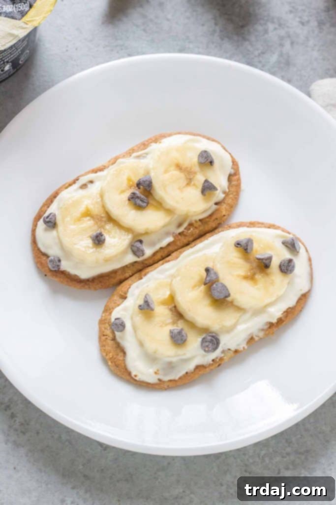 A close-up of a Mini Breakfast Biscuit Pizza with banana slices and mini chocolate chips on a cinnamon belVita biscuit.