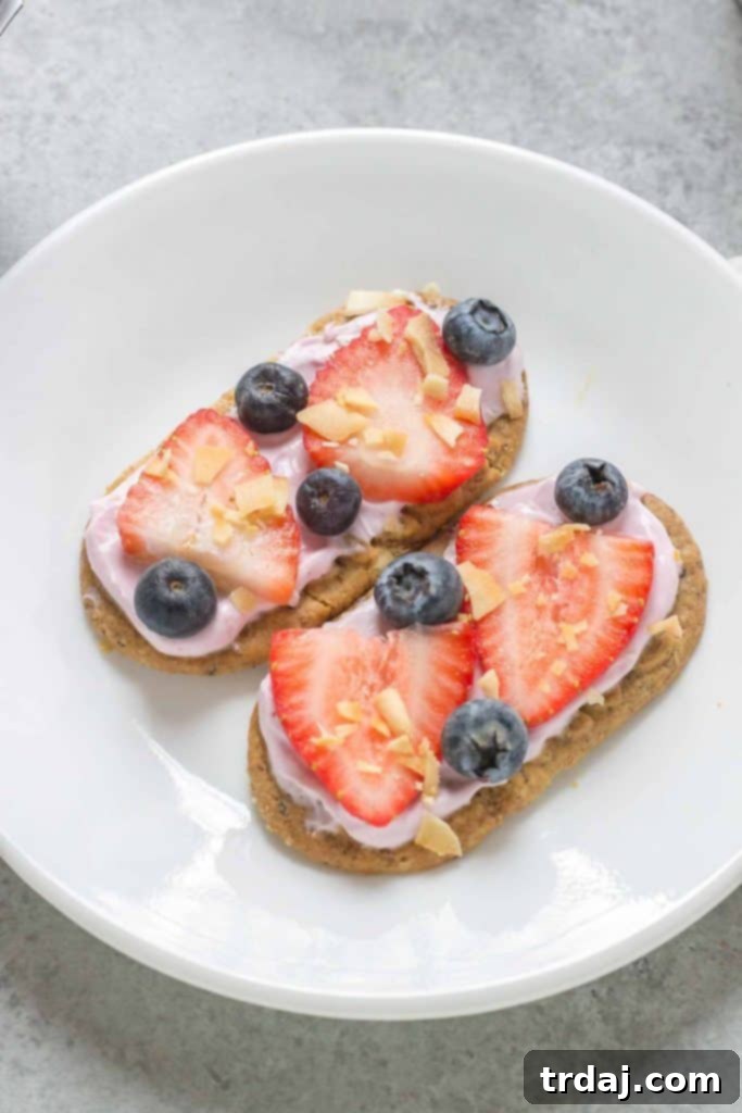 A blueberry belVita biscuit pizza topped with fresh strawberries, blueberries, and coconut flakes.