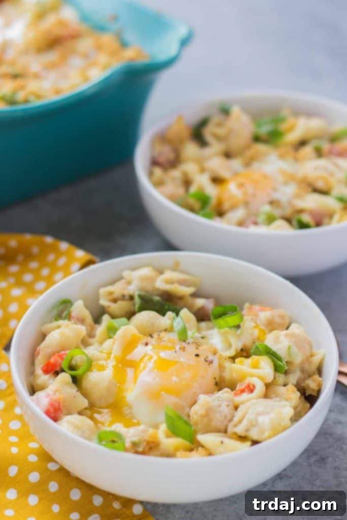 Breakfast Macaroni and Cheese with runny egg, brimming with cheesy goodness, ham, and fresh vegetables.