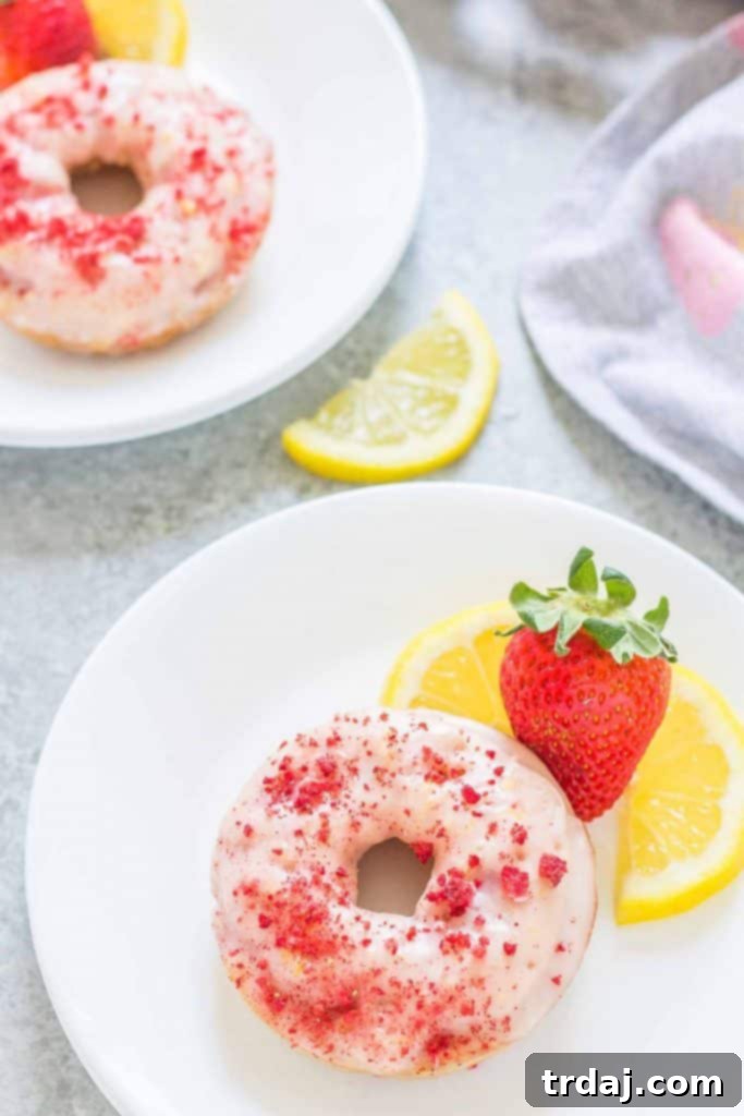 Enjoy the vibrant taste of summer with these homemade baked donuts. Freshly Baked Strawberry Lemonade Donuts with Zesty Glaze Drizzle