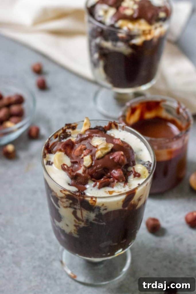 A top-down view of a serving of Hazelnut Pudding Cake, showcasing its glossy chocolate magic shell and chopped hazelnuts