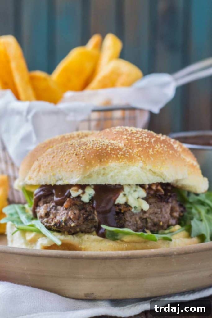 Close-up of a Peppercorn Blue Cheese Burger with Cherry Sauce, highlighting the texture of the patty and the rich toppings.
