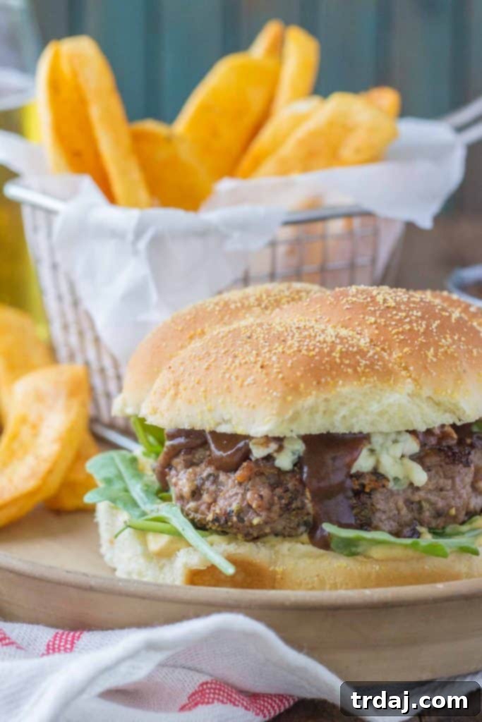 A gourmet Peppercorn Blue Cheese Burger with Cherry Sauce served with crispy steak fries.