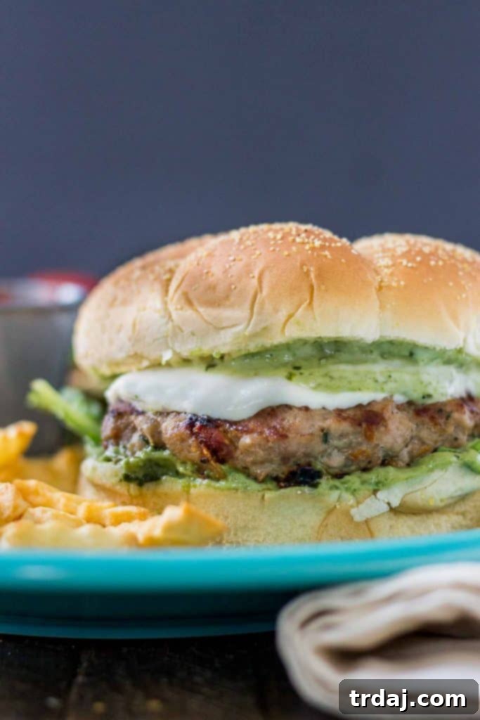 Finished Pesto and Sun Dried Tomato Turkey Burger on a bun, with melted mozzarella.